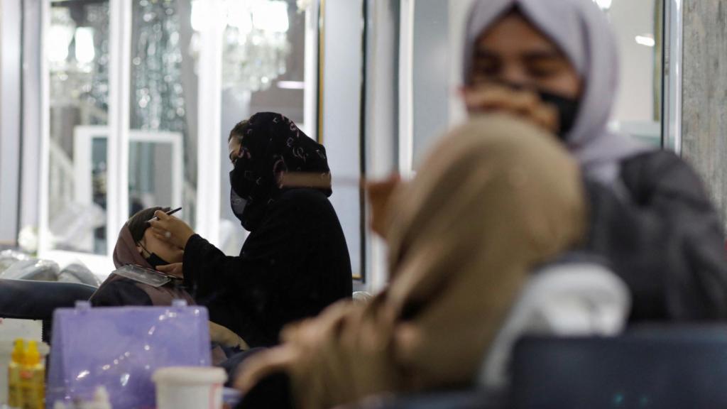 Esteticistas afganas aplican maquillaje a clientes en un salón de belleza en Kabul, Afganistán.