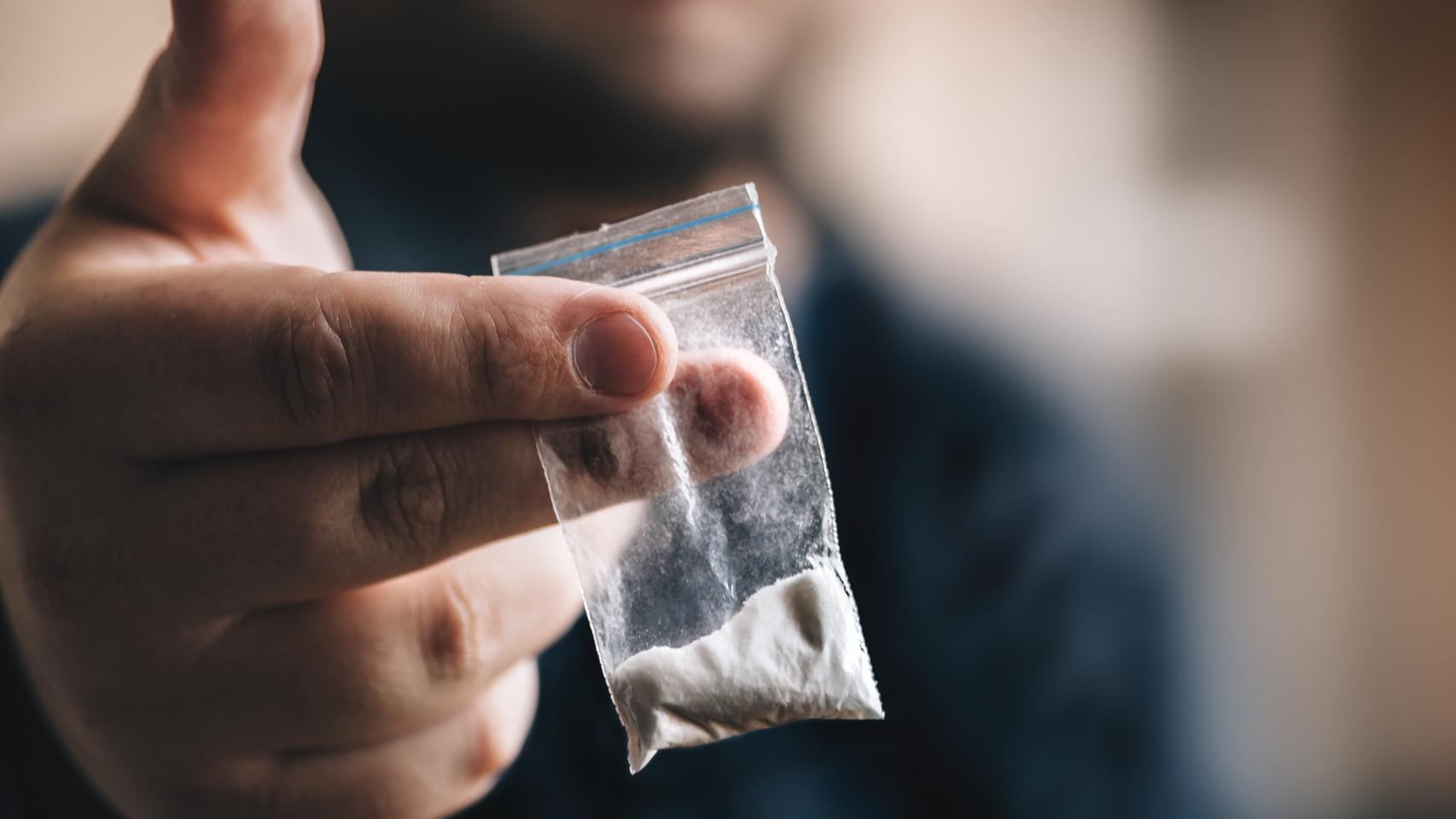 Una persona simula la entrega de cocaína a otra persona, en una imagen de archivo.