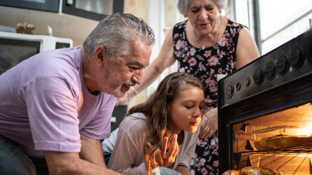 Unos abuelos con su nieta cocinando.