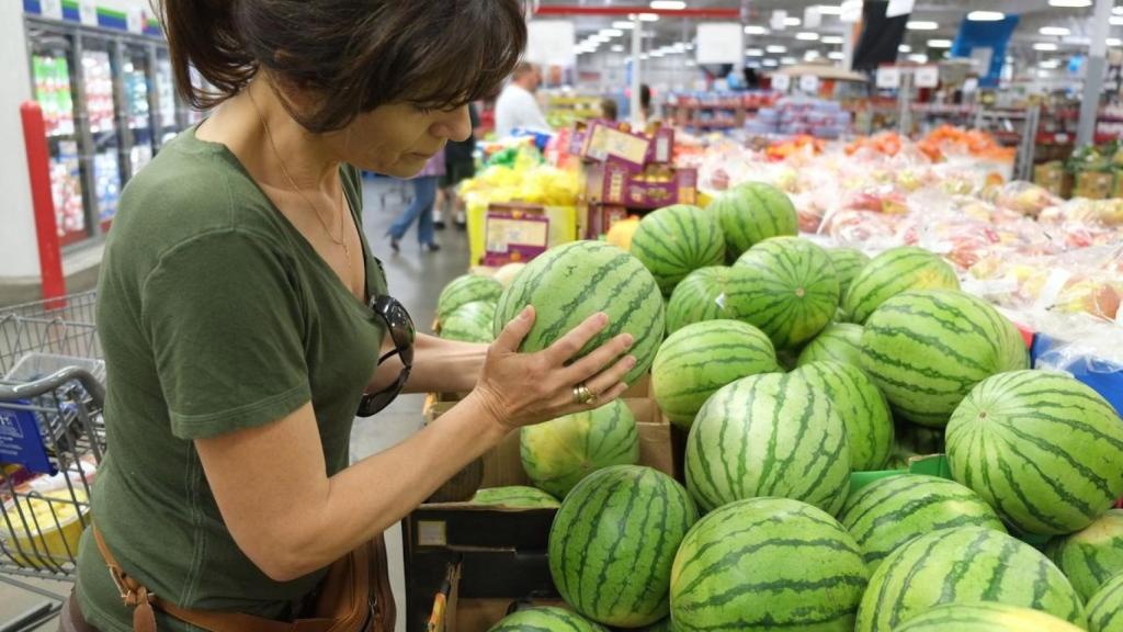 Una mujer eligiendo sandías en el supermercado.
