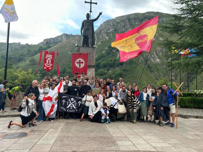 El padre Pich, con un grupo de peregrinos junto a sus estandartes, ante la estatua de don Pelayo.