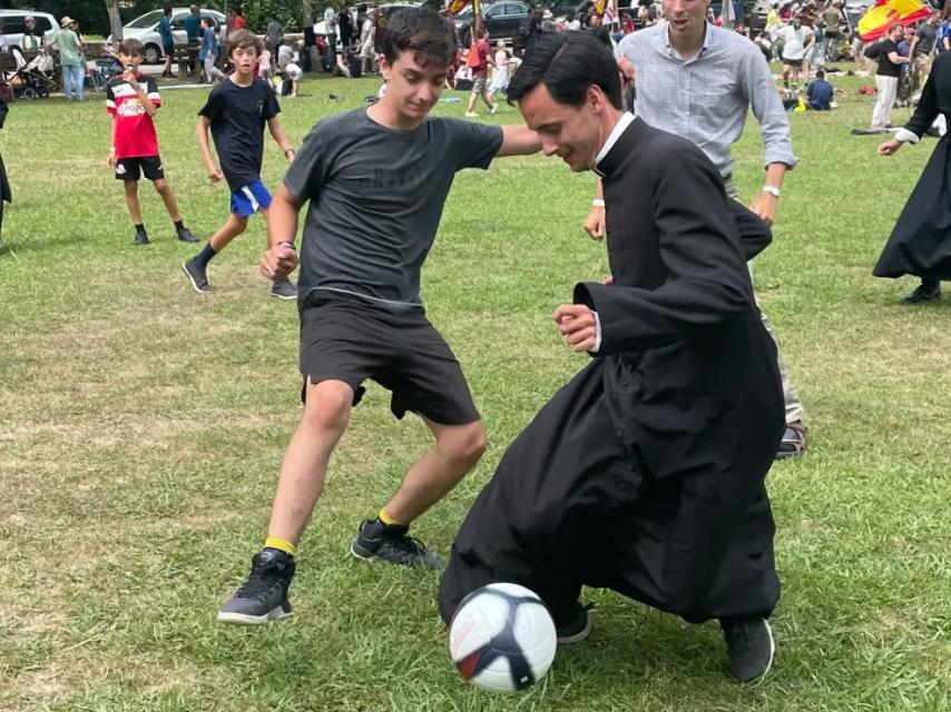 Un cura juega al fútbol con sotana en uno de los campamentos de la peregrinación.