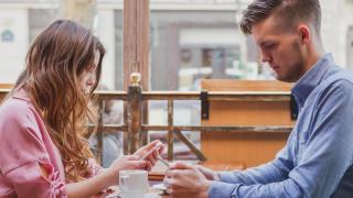 Una pareja se ignora mutuamente mirando el móvil.