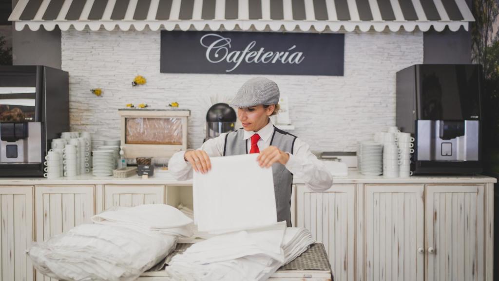 Una camarera, que luce el uniforme tradicional de chulapo, preparando el servicio de comidas.