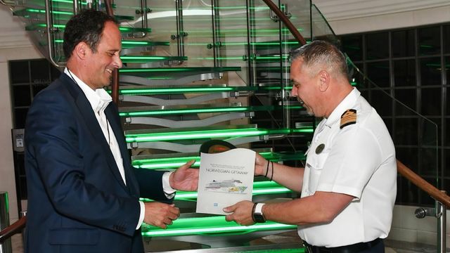 Carlos Botana intercambia una placa con el capitán del buque.