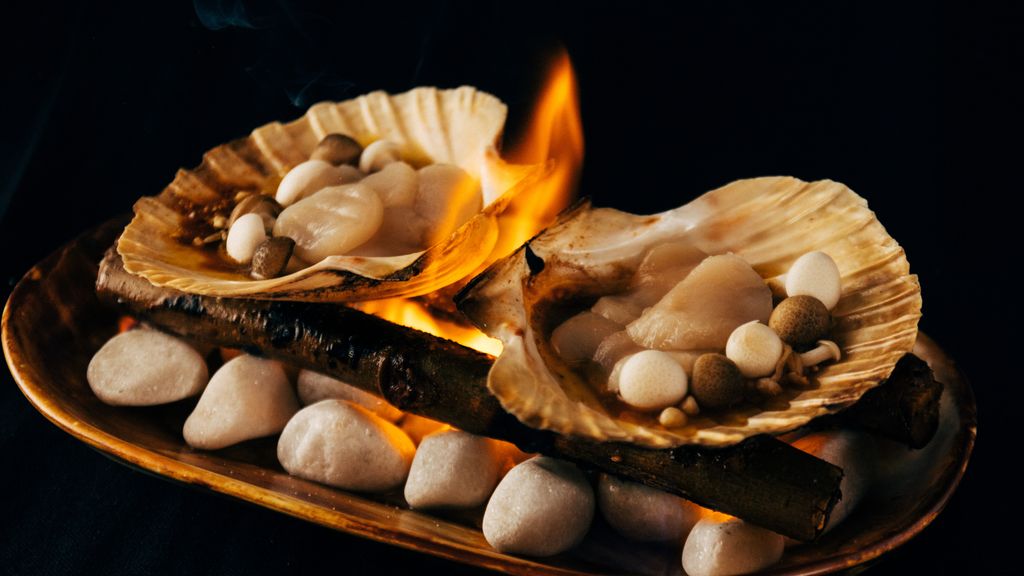 Un plato de vieiras con mantequilla en llamas.