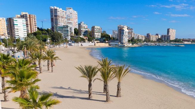 Una playa alicantina con apartamentos al fondo.
