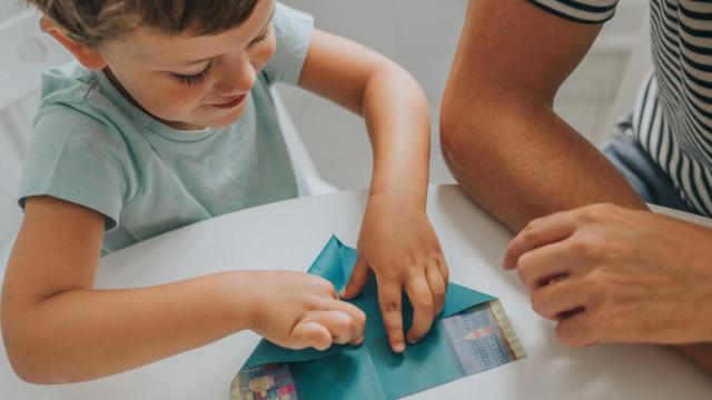 Un niño haciendo un avión de papel