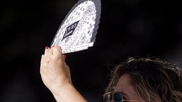 Una mujer camina por el centro de Málaga protegiéndose del sol.
