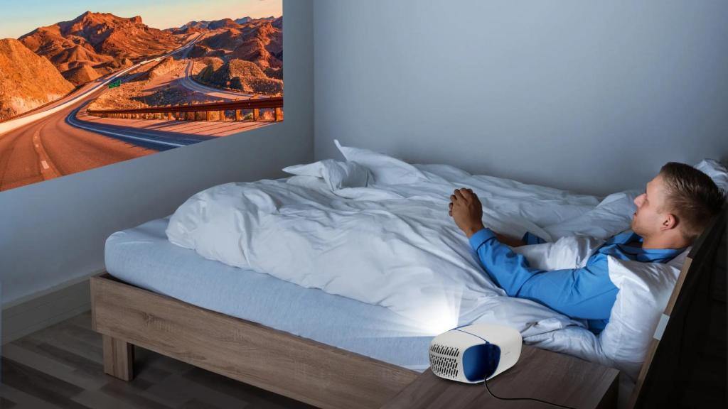 Una persona utilizando el mini proyector en el cuarto.