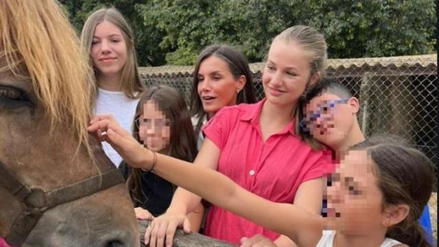 La reina Letizia y sus hijas, Leonor y Sofía, acariciando a un caballo mientras charlan con tres menores, este viernes 4 de agosto.