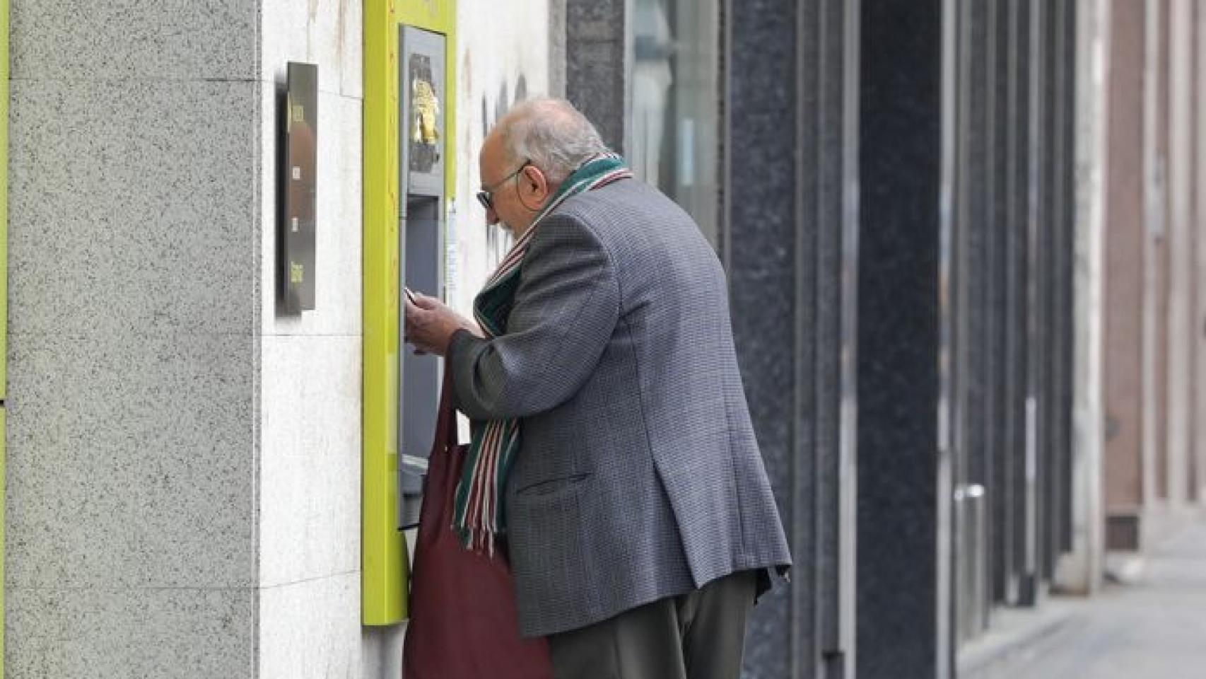 Un anciano sacando dinero de un cajero automático.