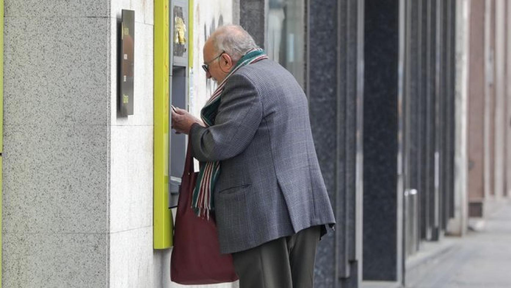 Un anciano sacando dinero de un cajero automático.