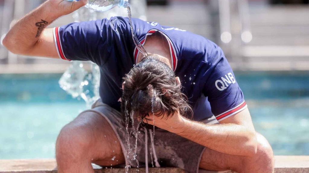 Joven se refresca echándose agua por encima en Madrid.