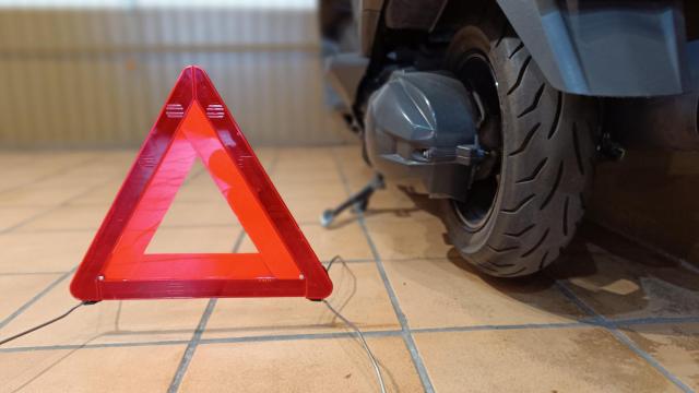 Un triángulo de señalización junto a un vehículo.