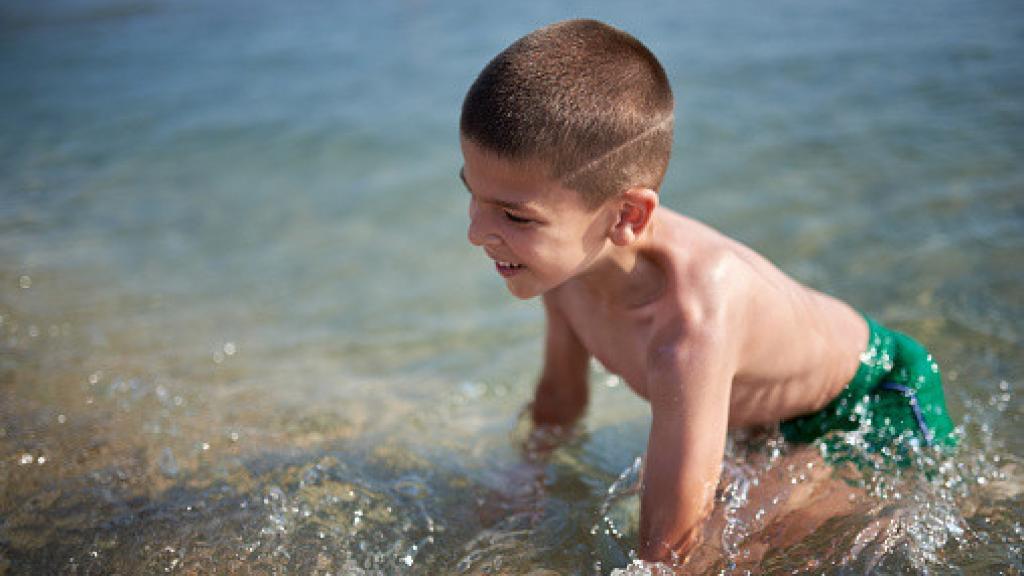 Imagen de archivo de un niño bañándose en la playa.