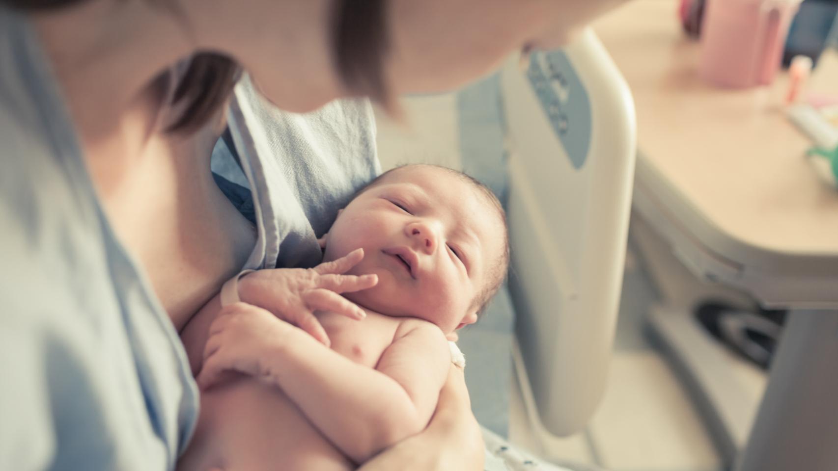 Una madre abraza a su hijo recién nacido en el hospital.
