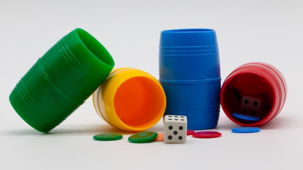 Taza de colores con fichas y dados para jugar al parchís.