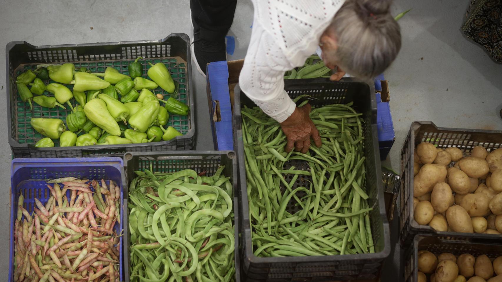 Una mujer compra verduras en un mercado.
