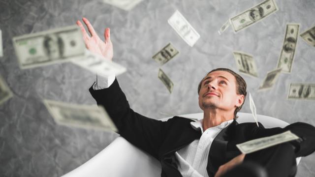 Un millonario lanza billetes.