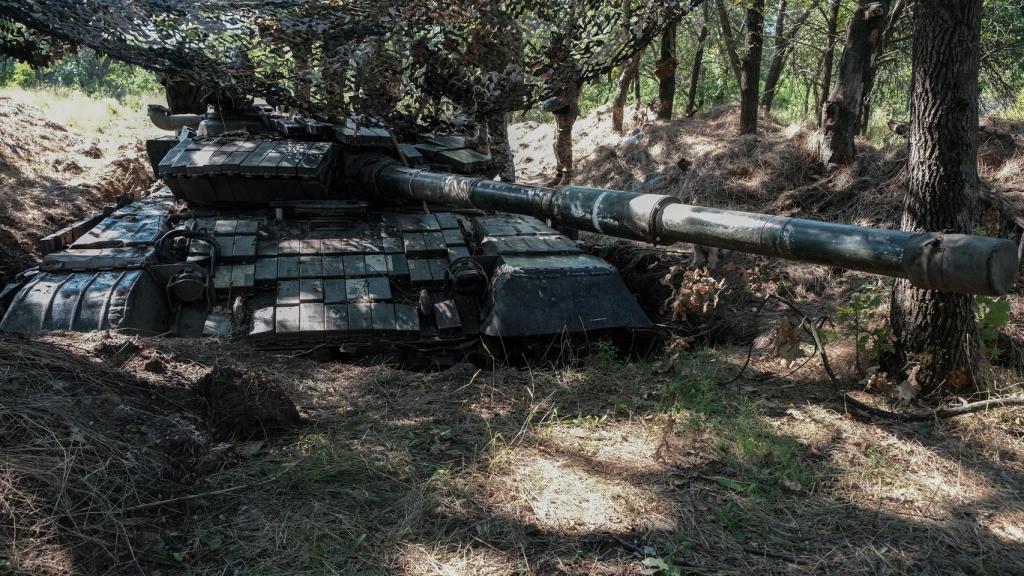 La tripulación de un carro de combate ucraniano T-64 realiza las tareas de mantenimiento bajo una red de camuflaje para protegerse de los drones rusos