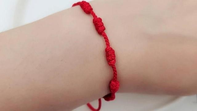 La pulsera roja de la suerte.
