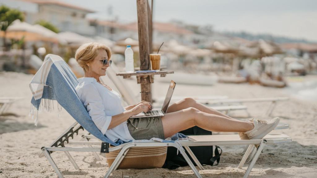Una mujer conectada a su empresa en la playa.