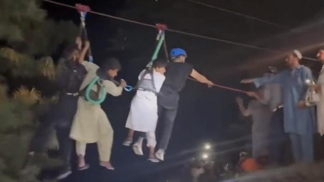 Dos agentes devuelven a tierra a dos de las ocho personas atrapadas en un teleférico en el norte de Pakistán.