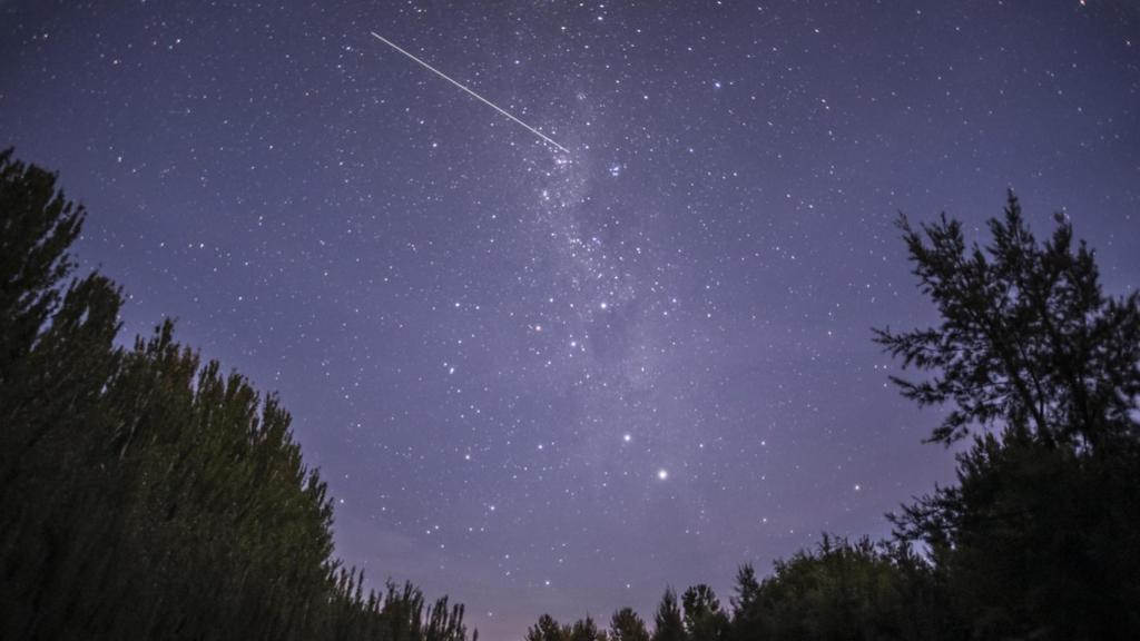 Cielo estrellado con una línea de Starlinks en la noche.