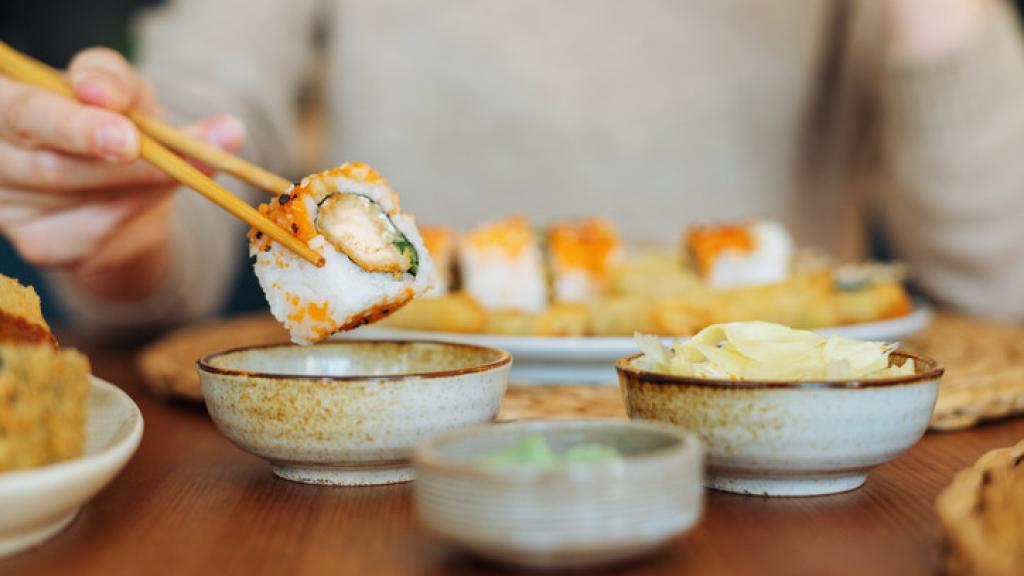 Una mujer comiendo un plato de sushi.