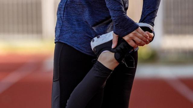 Una joven precalentando antes de correr.