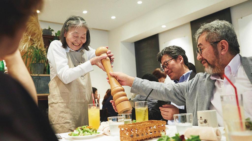 Una camarera trata de girar un molinillo de pimienta.