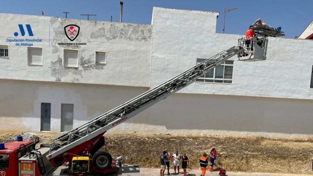 Los bomberos rescatando al obrero herido con la grúa.