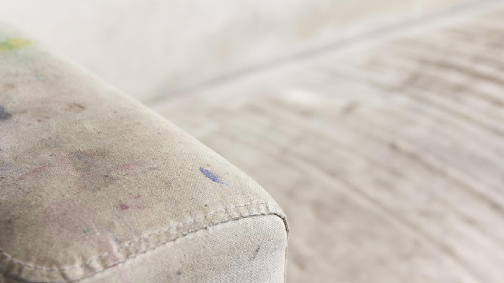 Detalle de un sofá con manchas de bolígrafo y café.