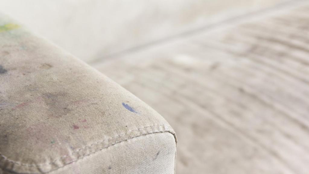 Detalle de un sofá con manchas de bolígrafo y café.