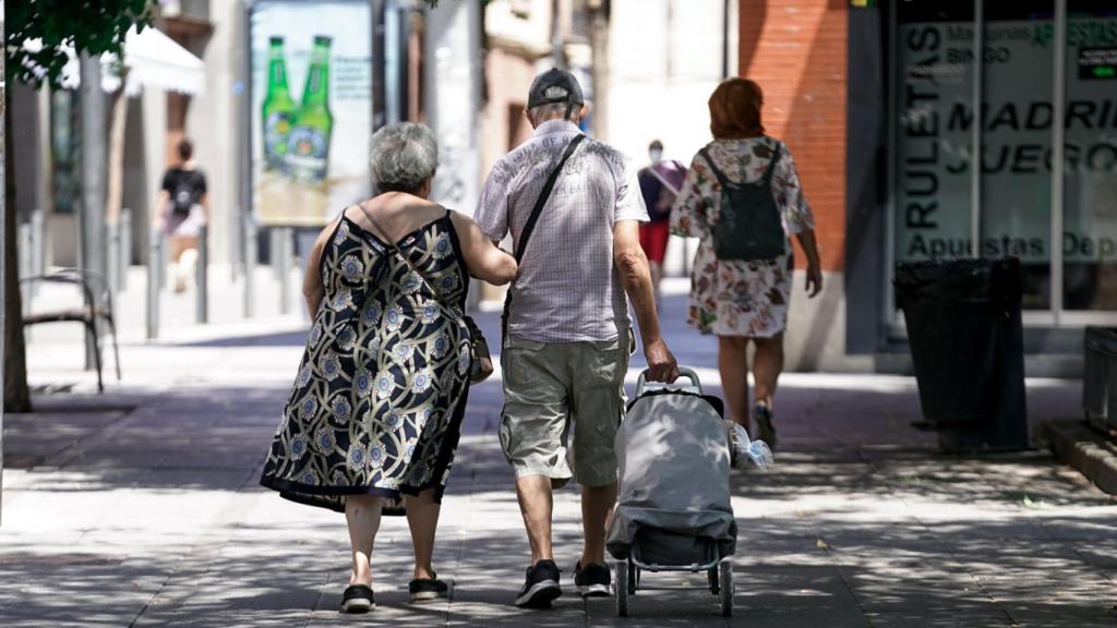 Dos ancianos paseando con un carro de la compra.