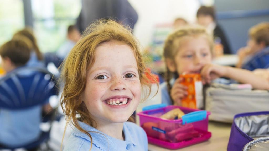 Una niña en el colegio comiendo.