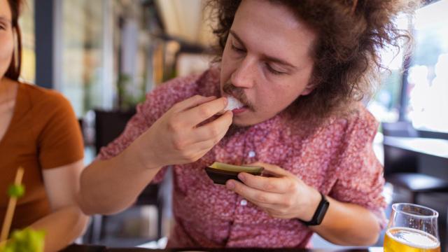 Imagen de archivo de un hombre comiéndose una pieza de sushi de un bocado.