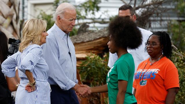 El presidente de Estados Unidos, Joe Biden, estrecha la mano de una mujer mientras recorren los destrozos causados por la tormenta del huracán Idalia en un barrio, 2 de septiembre de 2023.