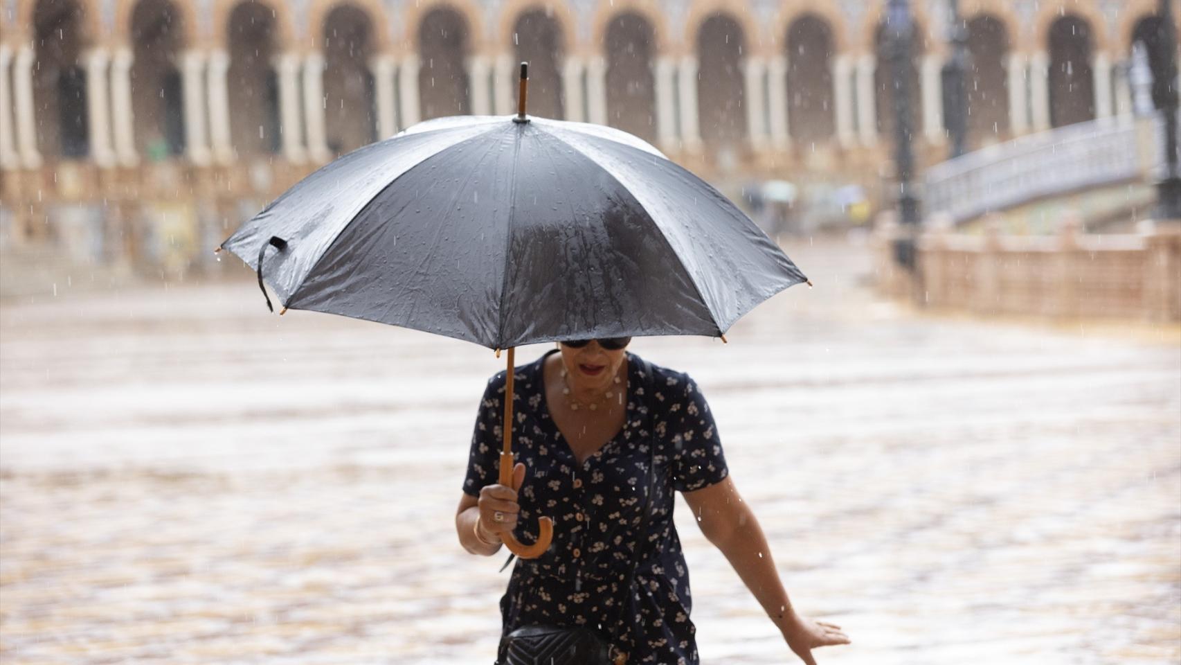 Una mujer se resguarda de la lluvia bajo su paraguas en Sevilla.