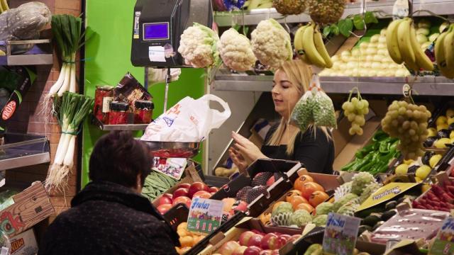 Un dependienta pesa una bolsa con frutas en las compras en los Mercados de Abastos en Sevilla.