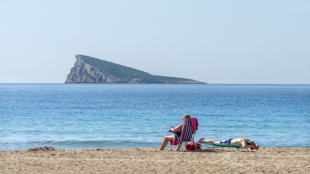 Una persona disfruta tomando el sol en una playa de Benidorm, Alicante