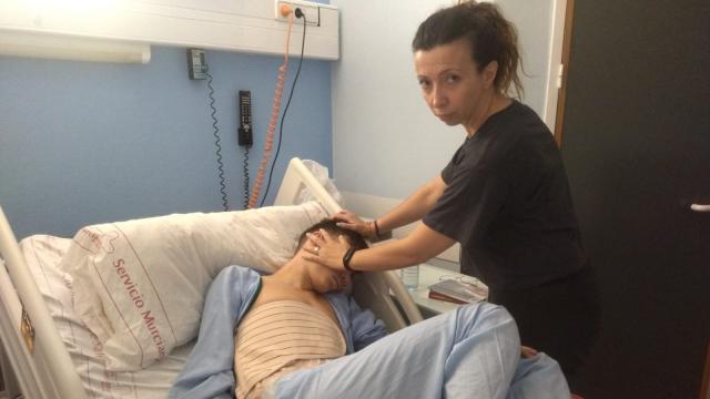 Carmen Jiménez, este domingo, acariciando a su hijo, Andrés, víctima de un apuñalamiento en Águilas.