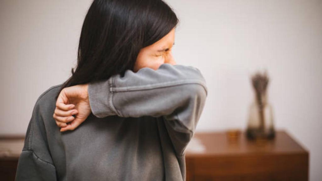 Una chica se cubre con su codo al tener un estornudo