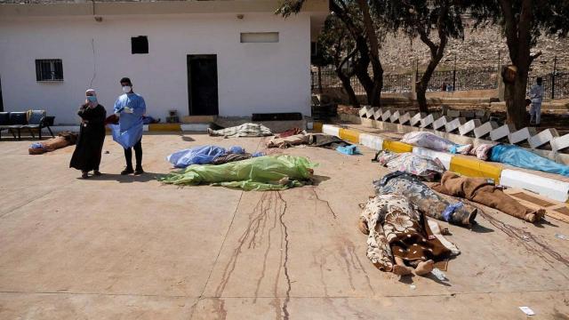 Dos supervivientes del ciclón, de pie junto a varios cadáveres, este martes en Derna.