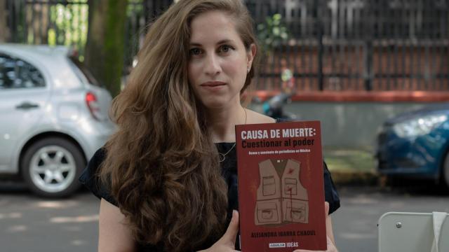 Ibarra sostiene con sus manos su último libro en el centro de la Ciudad de México