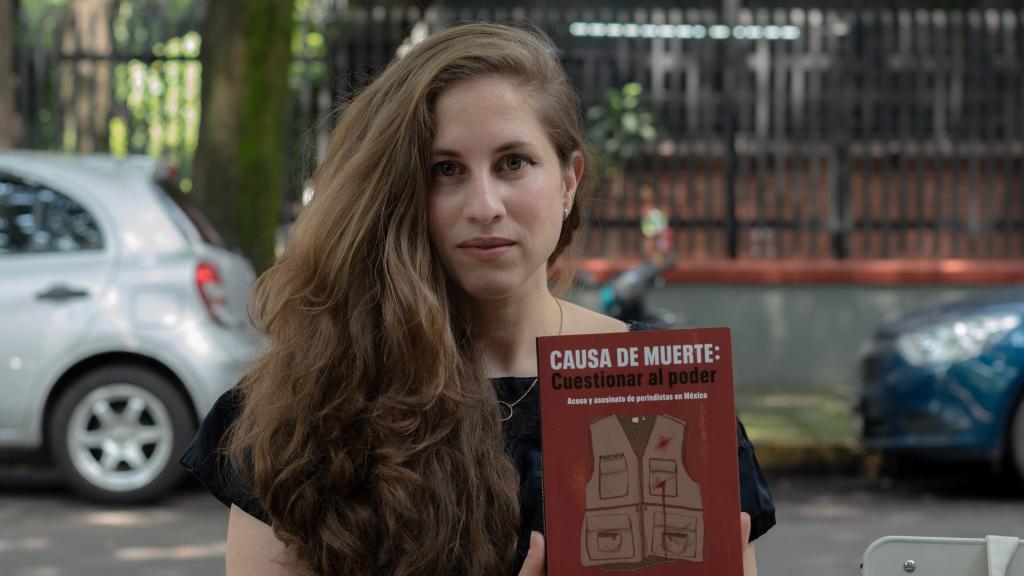 Ibarra sostiene con sus manos su último libro en el centro de la Ciudad de México