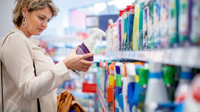 Una mujer mira la etiqueta de un producto de limpieza en un supermercado.