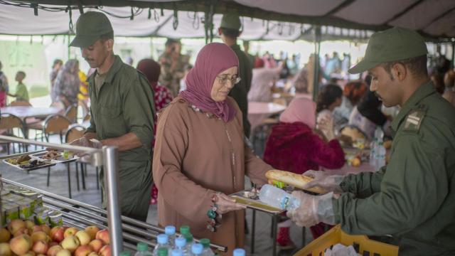 Un soldado marroquí entrega una bandeja de comida a una de las afectadas por el terremoto