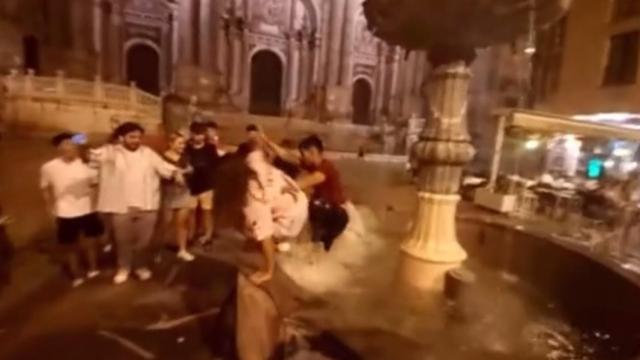 Varios jóvenes se bañan en la Fuente de la Plaza del Obispo, del siglo XVIII.